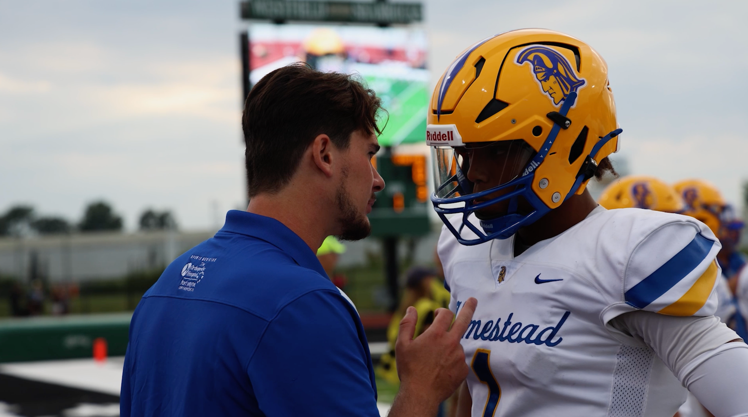 Coach speaking with a Homestead football player